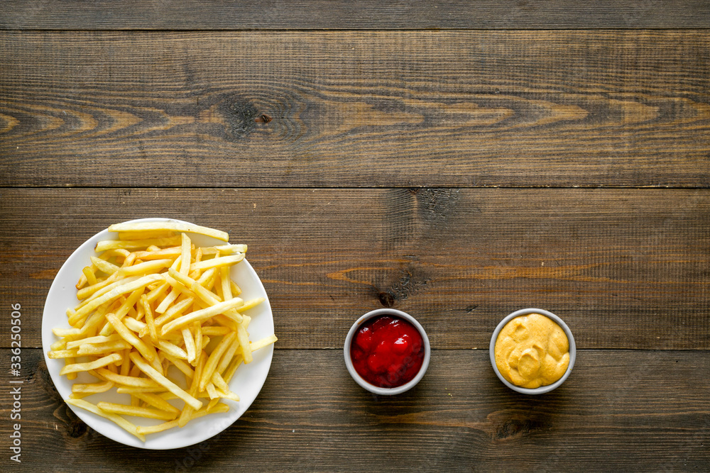 Fast food symbol. French fries on plate on dark wooden table top-down copy space