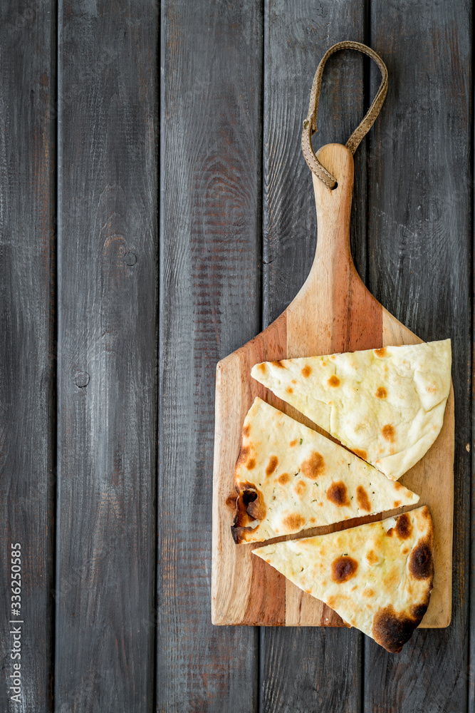 Make focaccia. Traditional italian bread on cutting board on dark wooden table top-down copy space