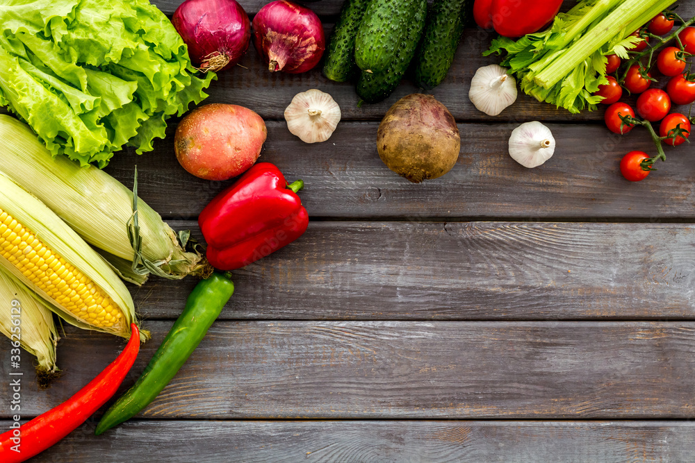 Set of autumn vegetables - potato, cucumber, carrot, greenery - on dark wooden background top-down c