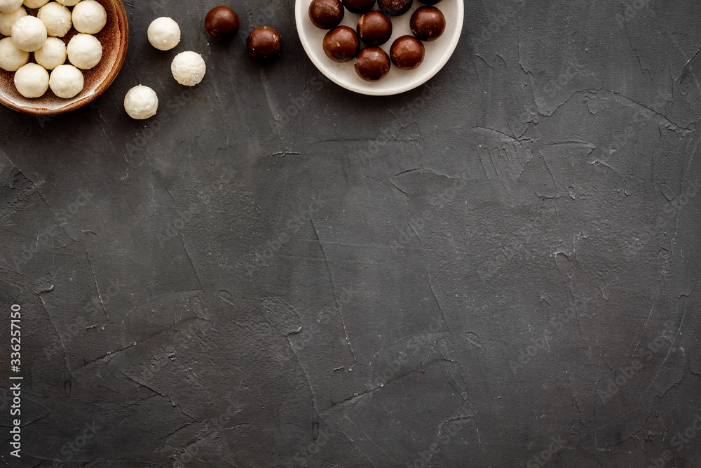 Sweets background with chocolate praline balls on grey desk top-down frame copy space