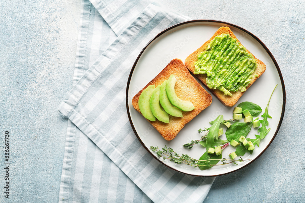 Plate with tasty avocado sandwiches on color background