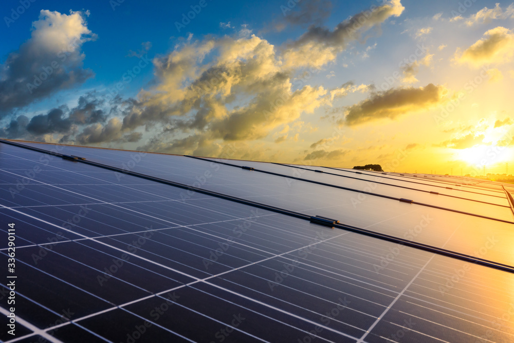 Photovoltaic solar panels and high voltage power lines at sunset sky background,green clean alternat