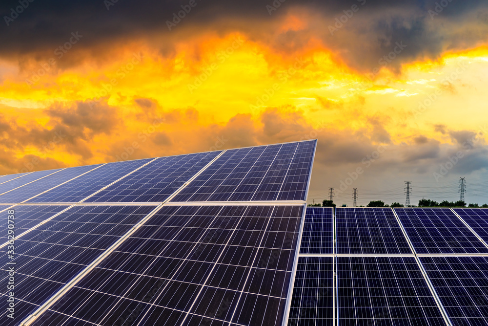 Photovoltaic solar panels and high voltage power lines at sunset sky background,green clean alternat