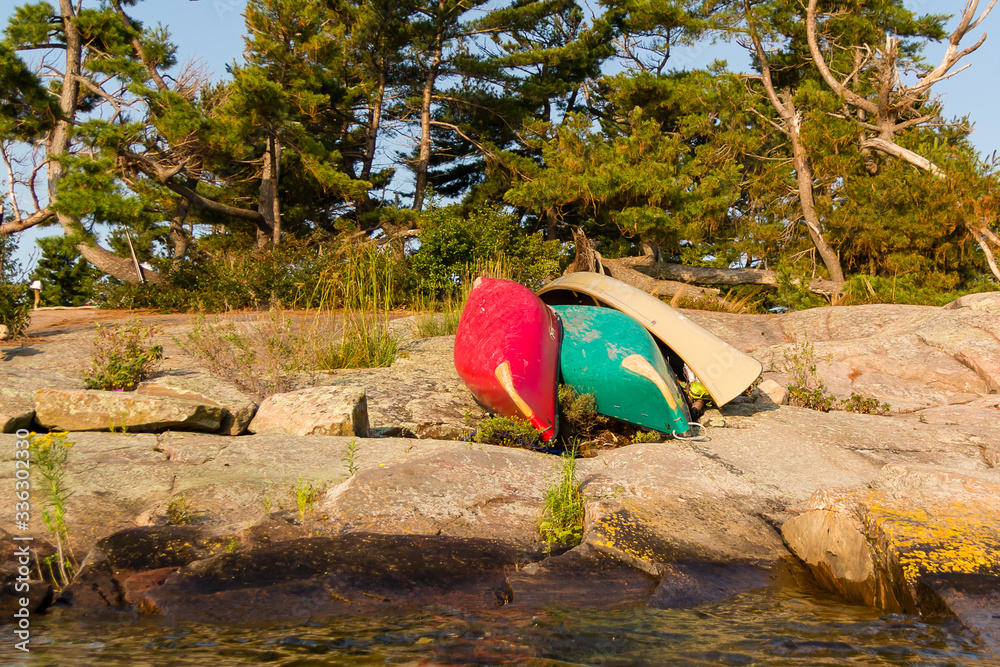 Red and green canoe sitting on the rugged coast of Georgian Bay