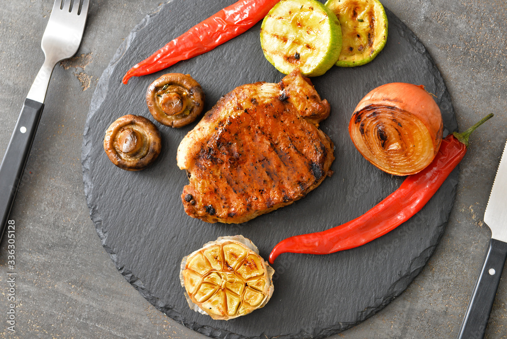 Cooked pork steak and vegetables on slate plate