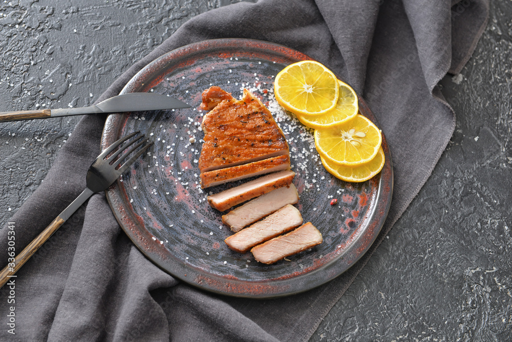 Plate with cooked pork steak on dark background