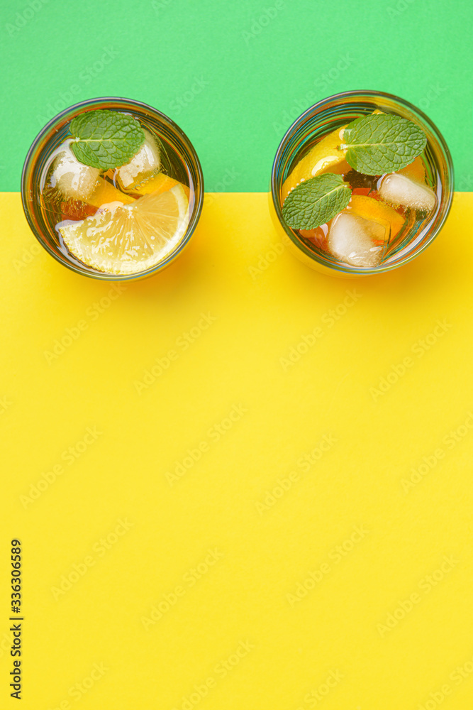 Glasses of tasty cold ice tea on color background