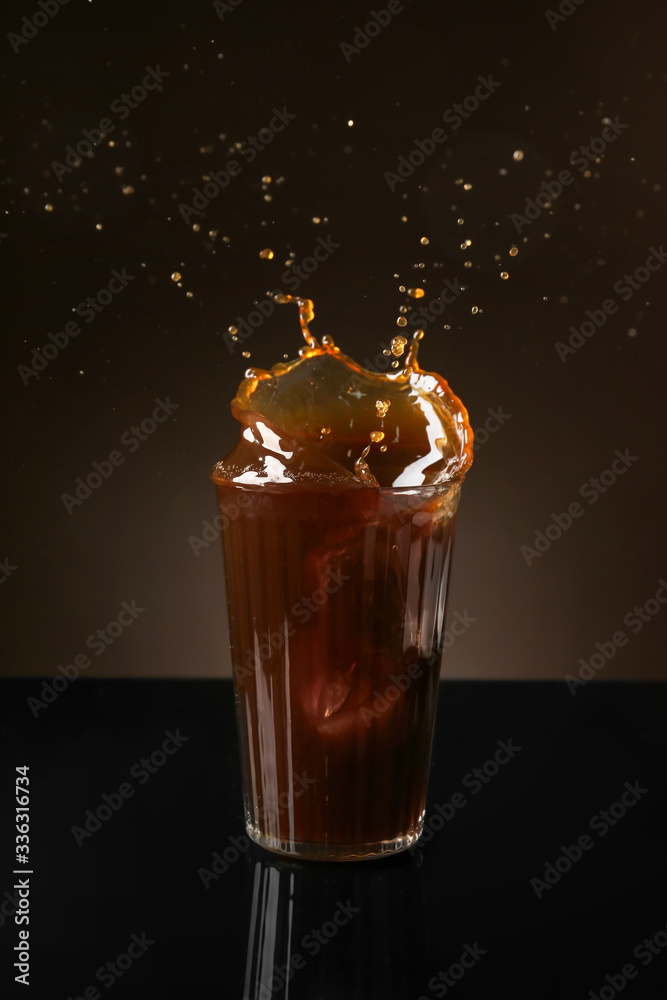 Splashing of coffee in glass on dark background