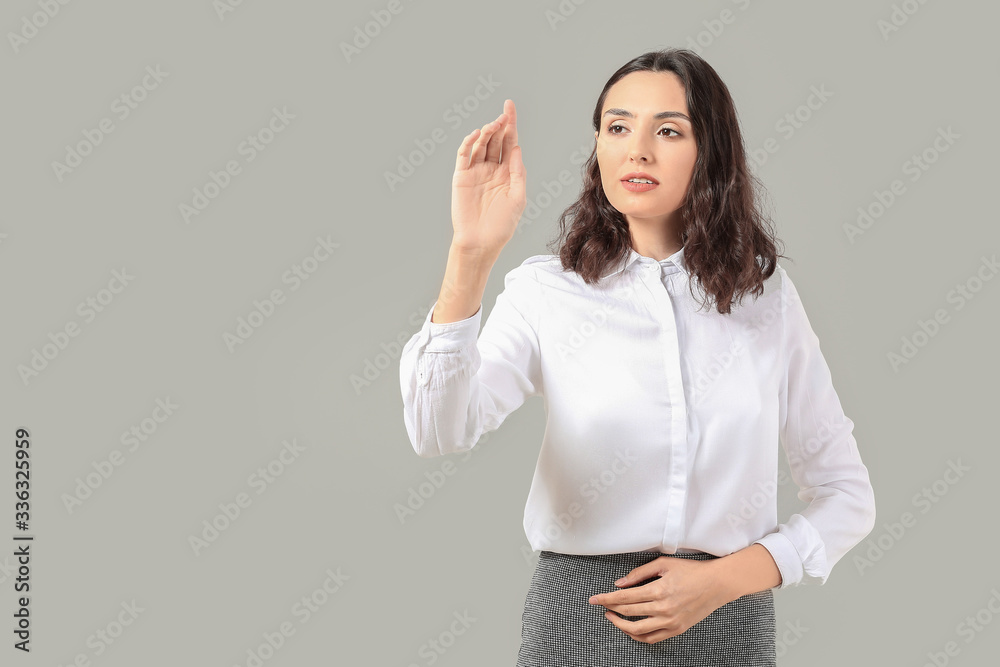 Businesswoman using virtual screen on grey background