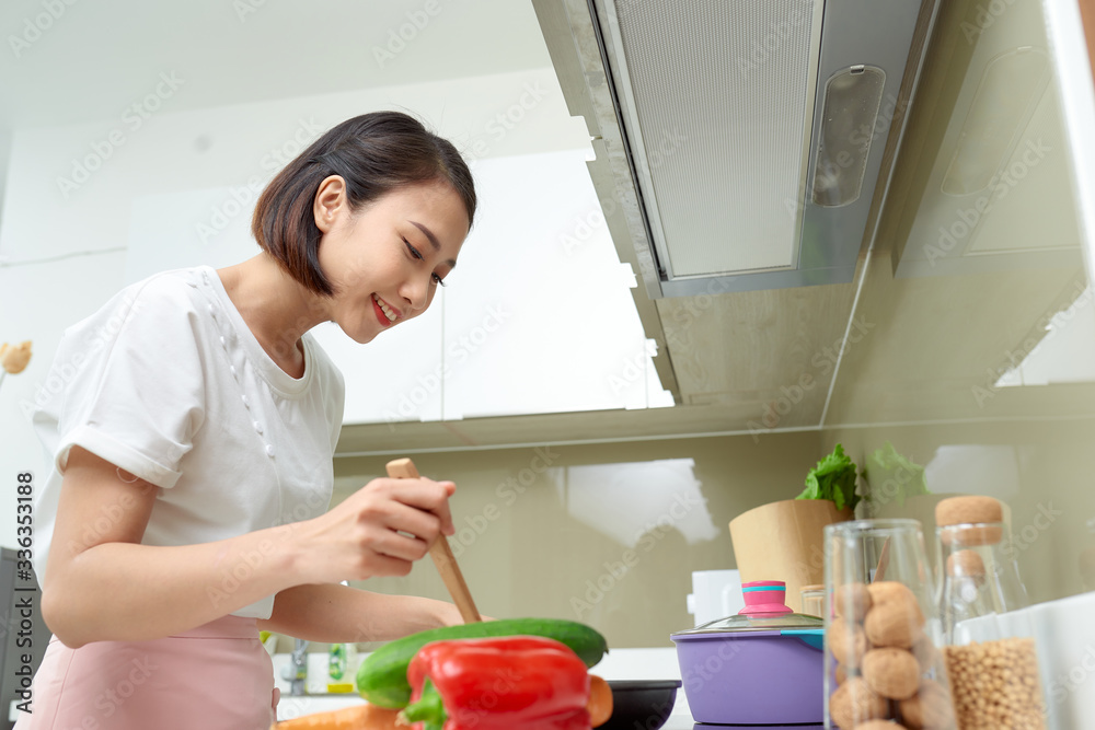 厨房里用木勺做饭的女人