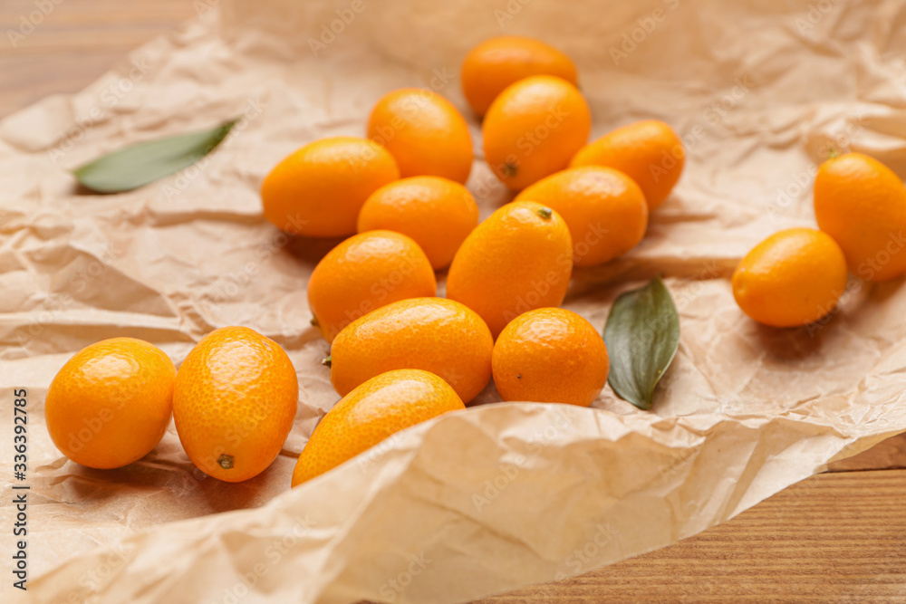 Parchment with tasty kumquat fruit on table, closeup