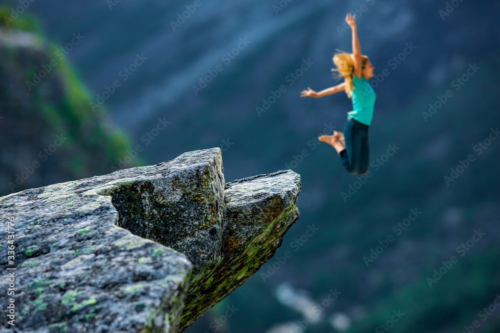 Frau springt im Gebirge von einem Fels