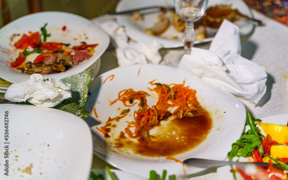 餐厅餐桌上用餐后脏盘子和杯子的俯视图。剩下的食物都是脏的