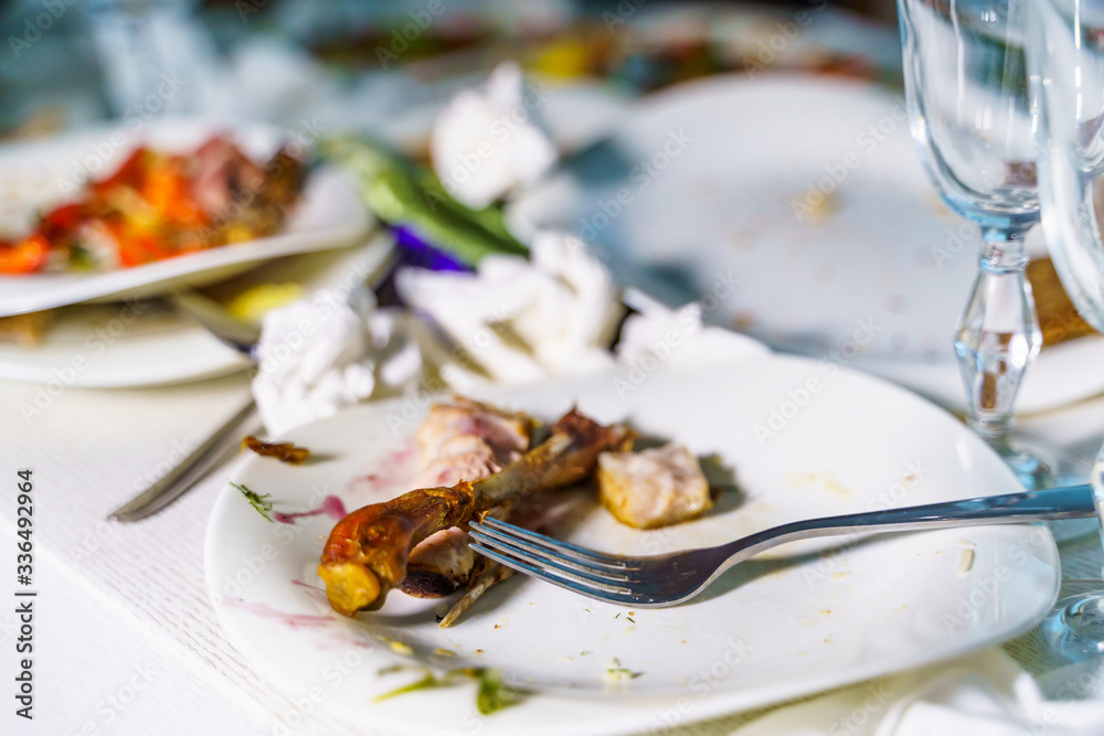 The leftover food and dirty dishes on the restaurant table. Scraps left over after the party.