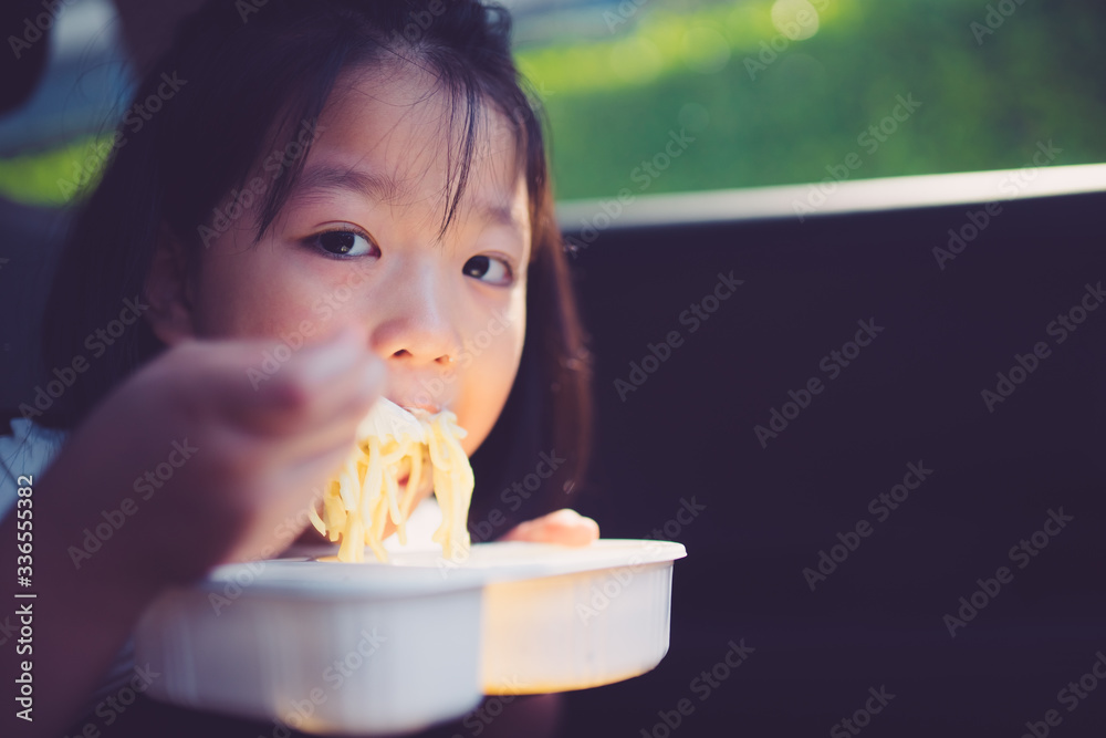 亚洲小女孩喜欢在车里用盒装意大利肉酱面和奶酪一起吃。