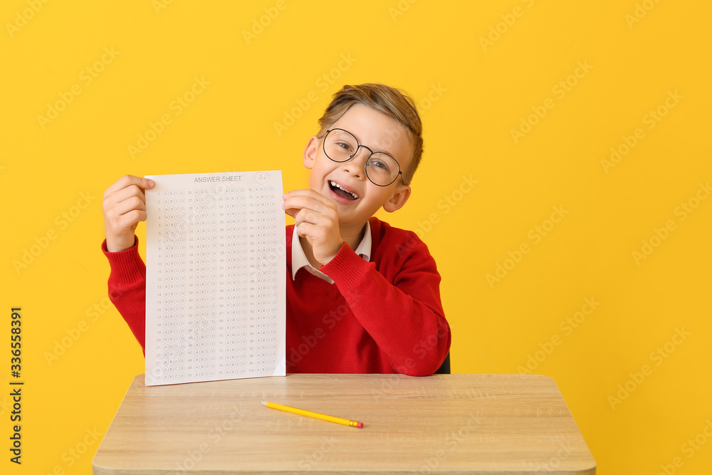 Pupil with answer sheet for school test on color background