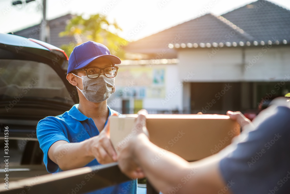 Asian delivery man wearing mask delivers parcel, customer in medical gloves signs on tablet. Deliver