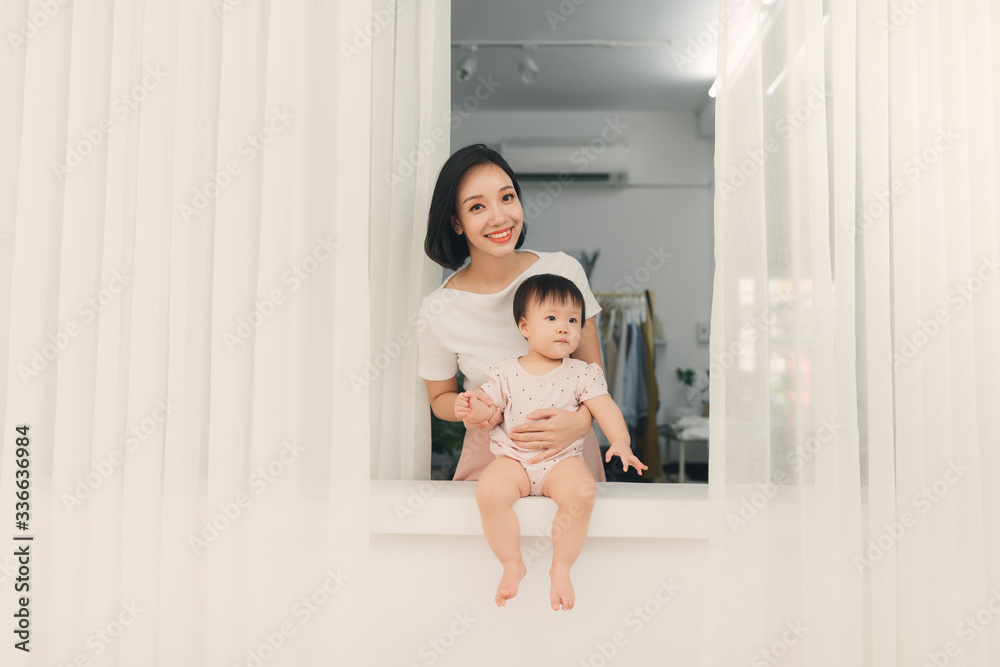 母亲和女儿坐在靠近窗户的窗台上