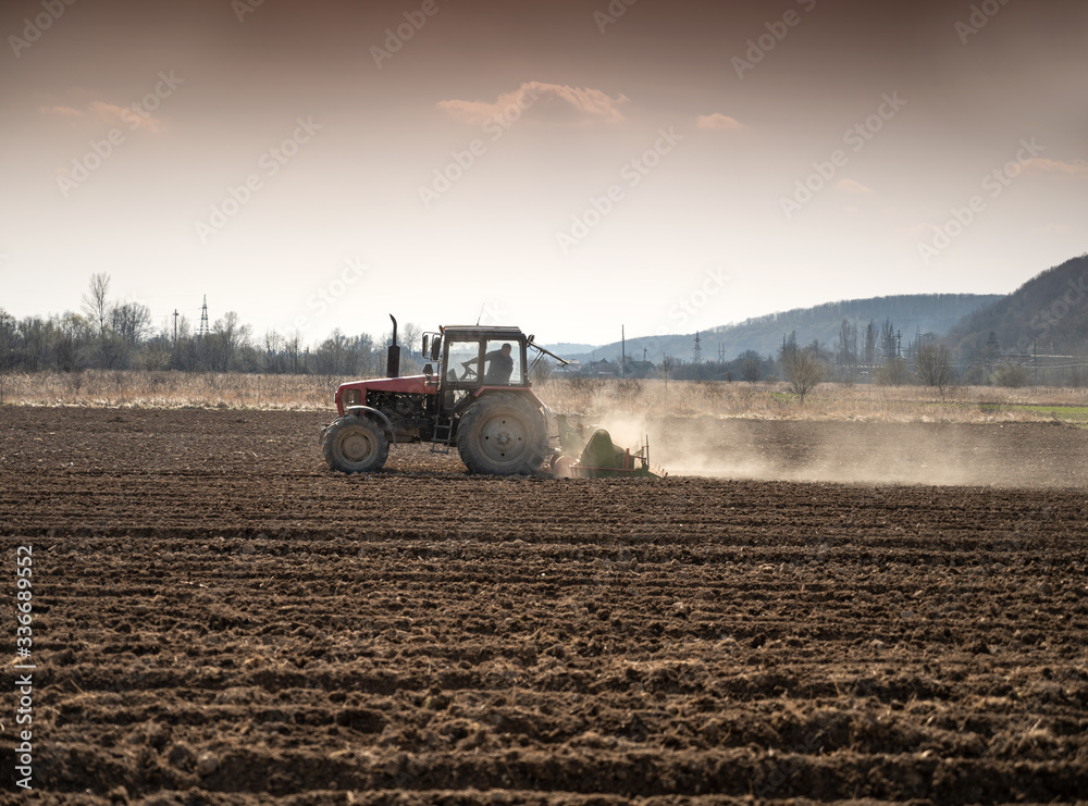 Farmer in tractor preparing land with seedbed cultivator in early spring