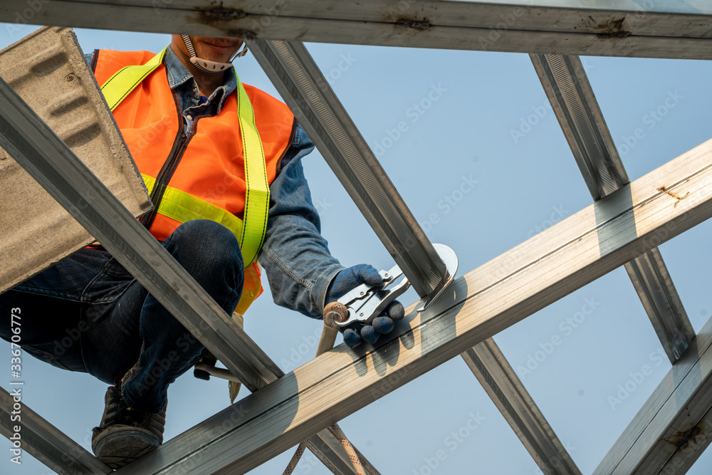 Construction worker wearing safety harness and safety line working at high place are installing new 