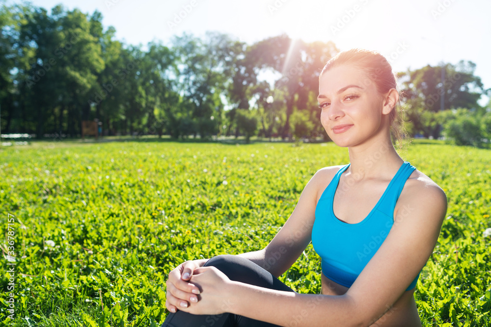 Beautiful smiling girl in activewear relax in park