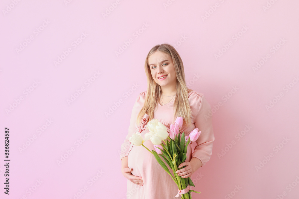 Beautiful pregnant woman with flowers on color background