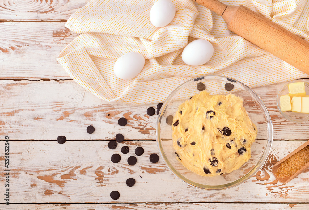 Bowl with sweet dough and products on table