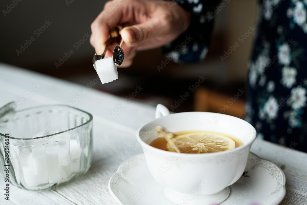 一位女士为她那杯美味的热柠檬茶准备了一块方糖