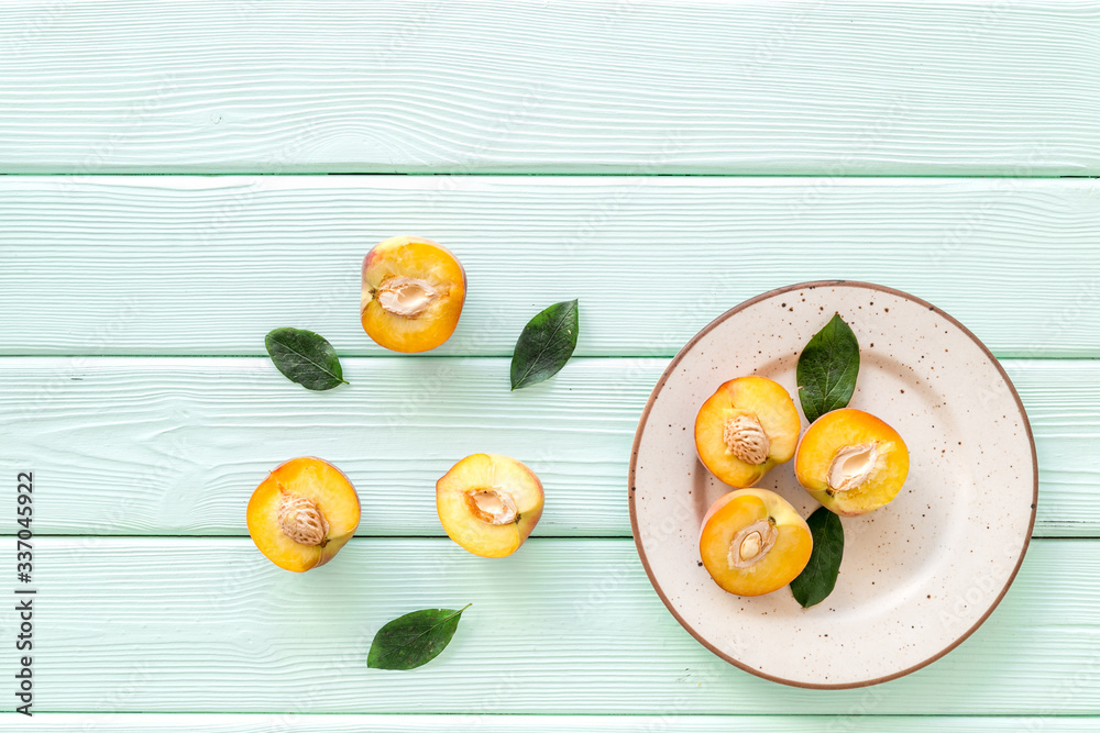 Healthy food. Ripe sliced peaches on plate on green wooden table top-down