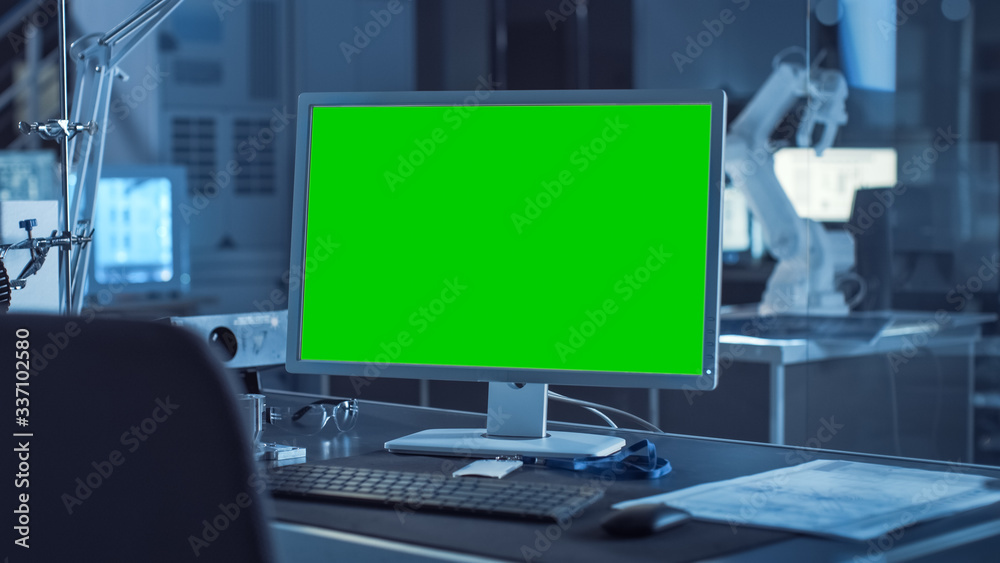 On the Desk Computer with Isolated Green Mock-up Screen Display. In the Background Robot Arm Concept