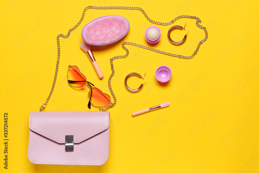 Stylish bag with female accessories on color background