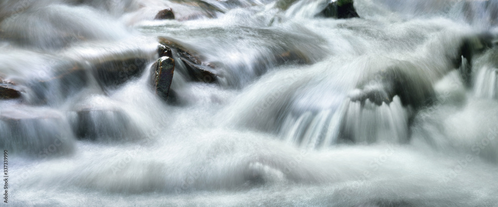 Streams of water beautifully cascading down a wild small river, panoramic format and long exposure f