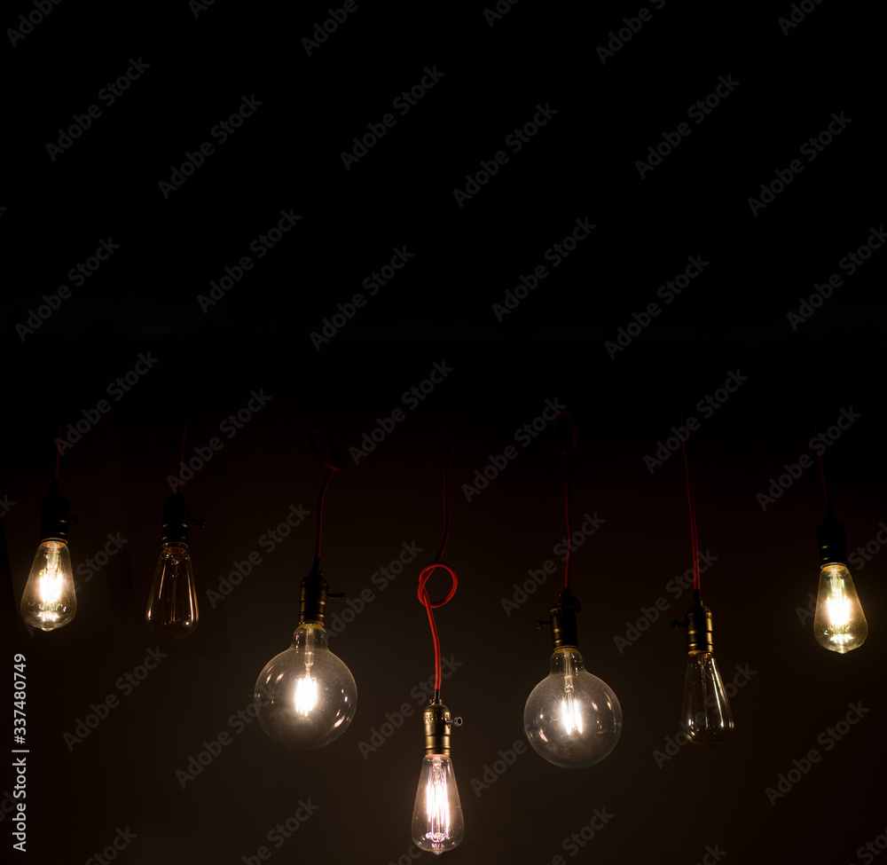 Old vintage light bulb on the wires hanging from the ceiling in the total darkness home decoration b