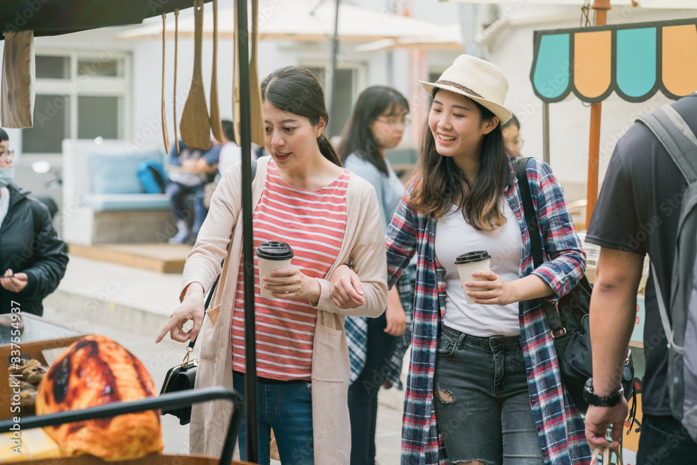 Happy girlfriends sharing time together outdoors in creative market on weekends. young female friend