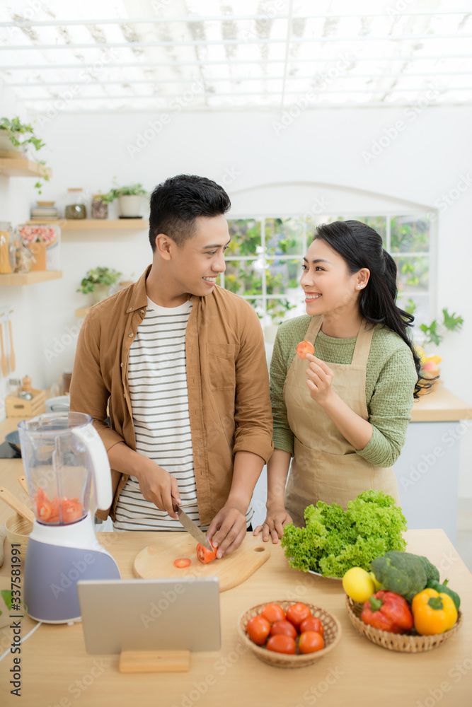 年轻的亚洲夫妇。站在厨房里做饭。