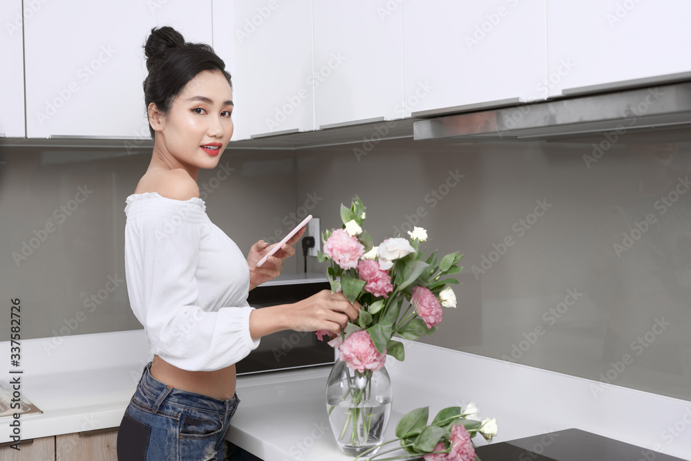 亚洲女人在厨房里与鲜花合影。