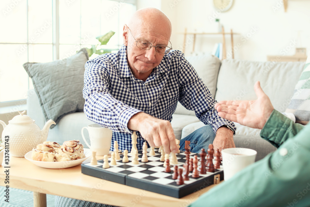 Elderly men playing chess at home