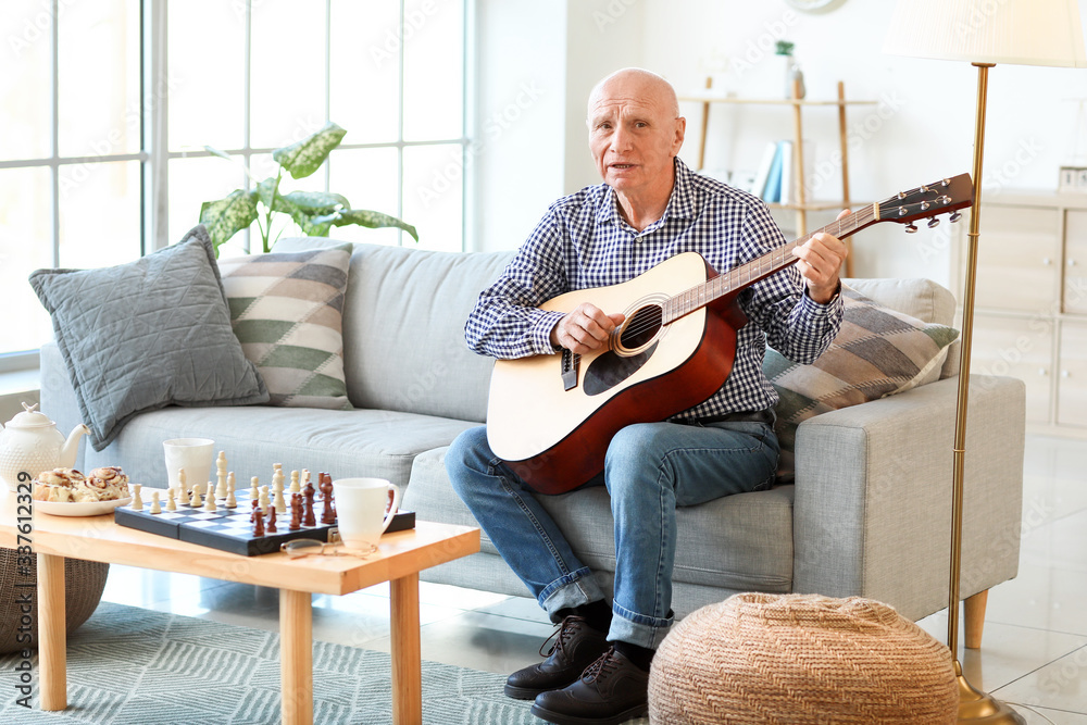 Elderly man playing guitar at home