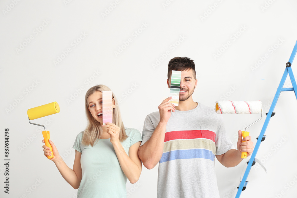 Young couple with color swatches and paint roller on white background