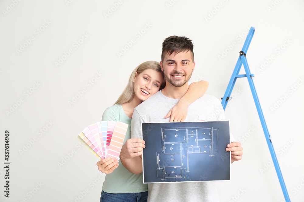 Young couple with plan of house and color swatches on white background