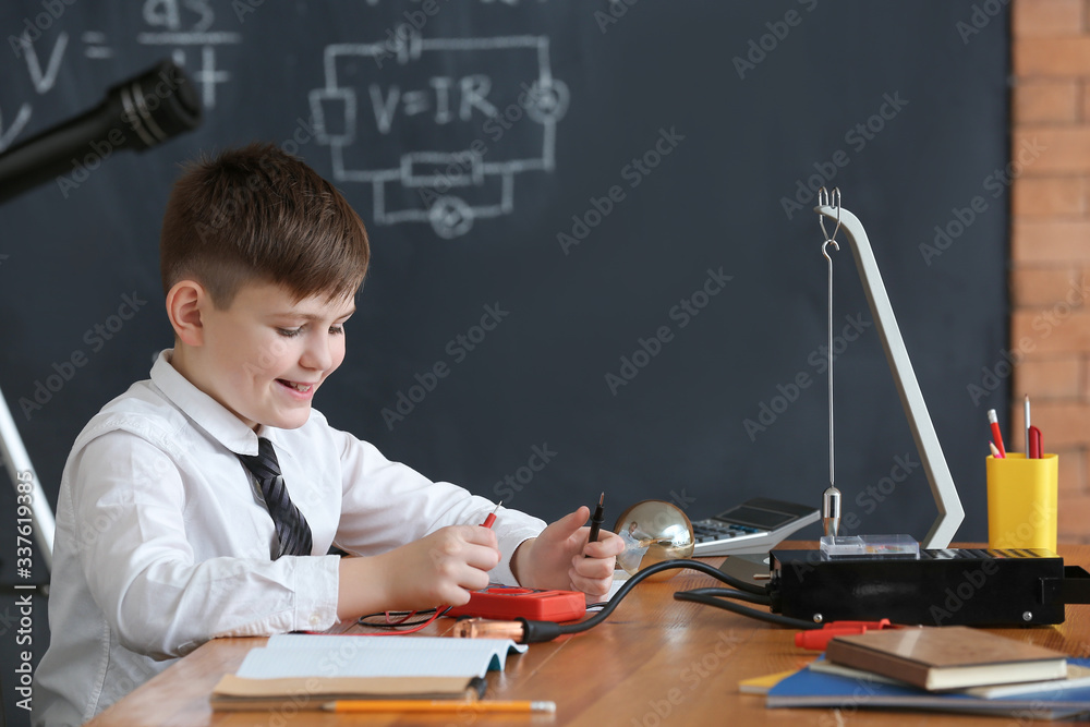 Cute little boy at physics lesson in classroom