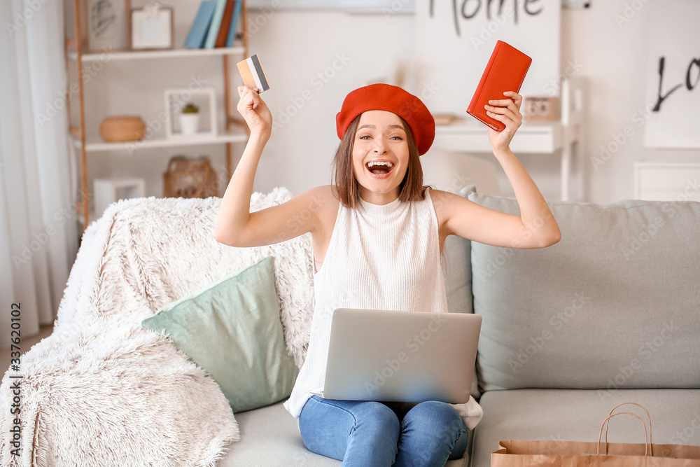 Happy woman with laptop, wallet and credit card at home. Online shopping concept