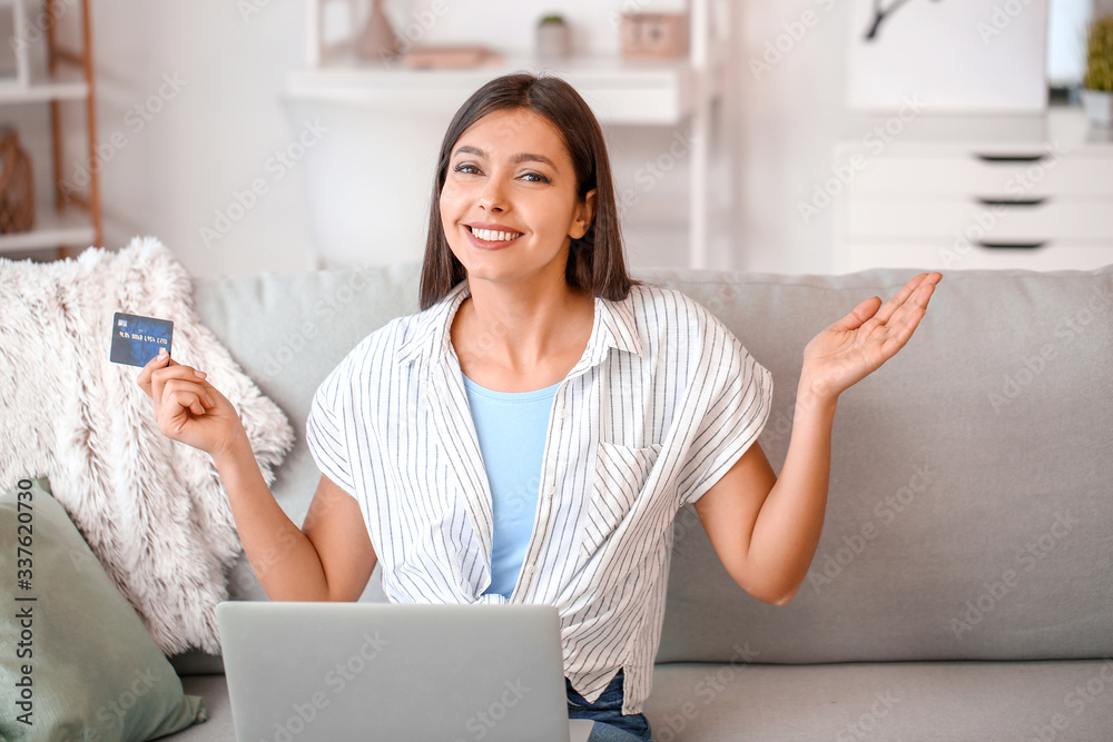 Young woman with laptop and credit card at home. Online shopping concept