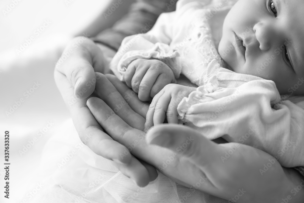 Mothers holding tiny hands of little baby, closeup