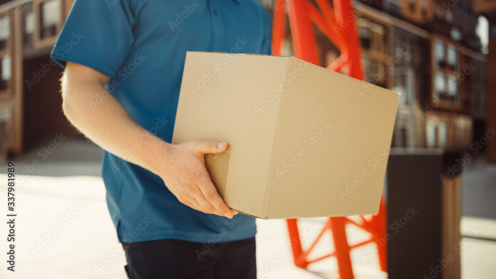 Delivery Man Holds Cardboard Box Package Walks Through Modern Stylish Business District. Courier On 