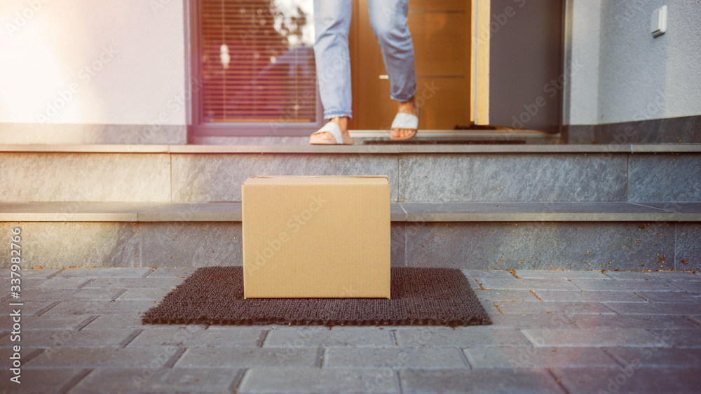 Delivered Cardboard Box Package on the Porch, Anonymous Woman stands on the Background. Close-up Low