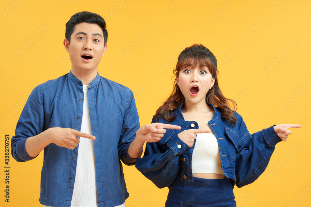 Beautiful young asian couple over white isolated background cheerful with a smile of face pointing w