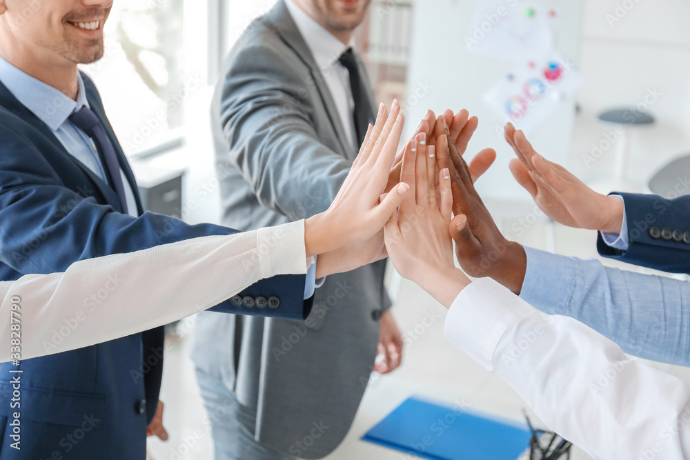 Group of business people putting hands together in office. Unity concept