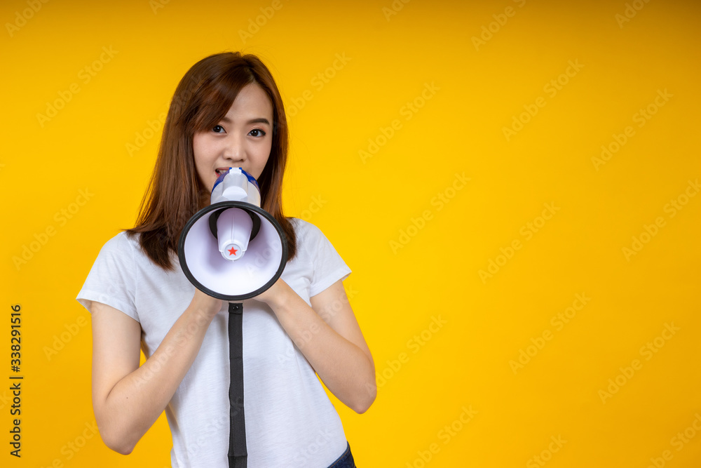 Young Asian woman in white casual t-shirt looking aside, scream in megaphone isolated on bright yell