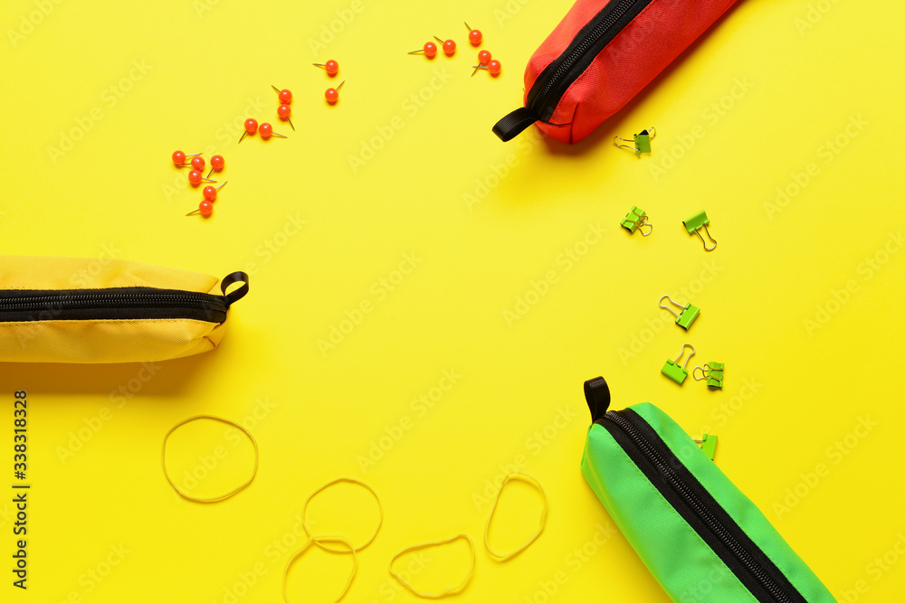 Frame made of pencil bags with stationery on color background